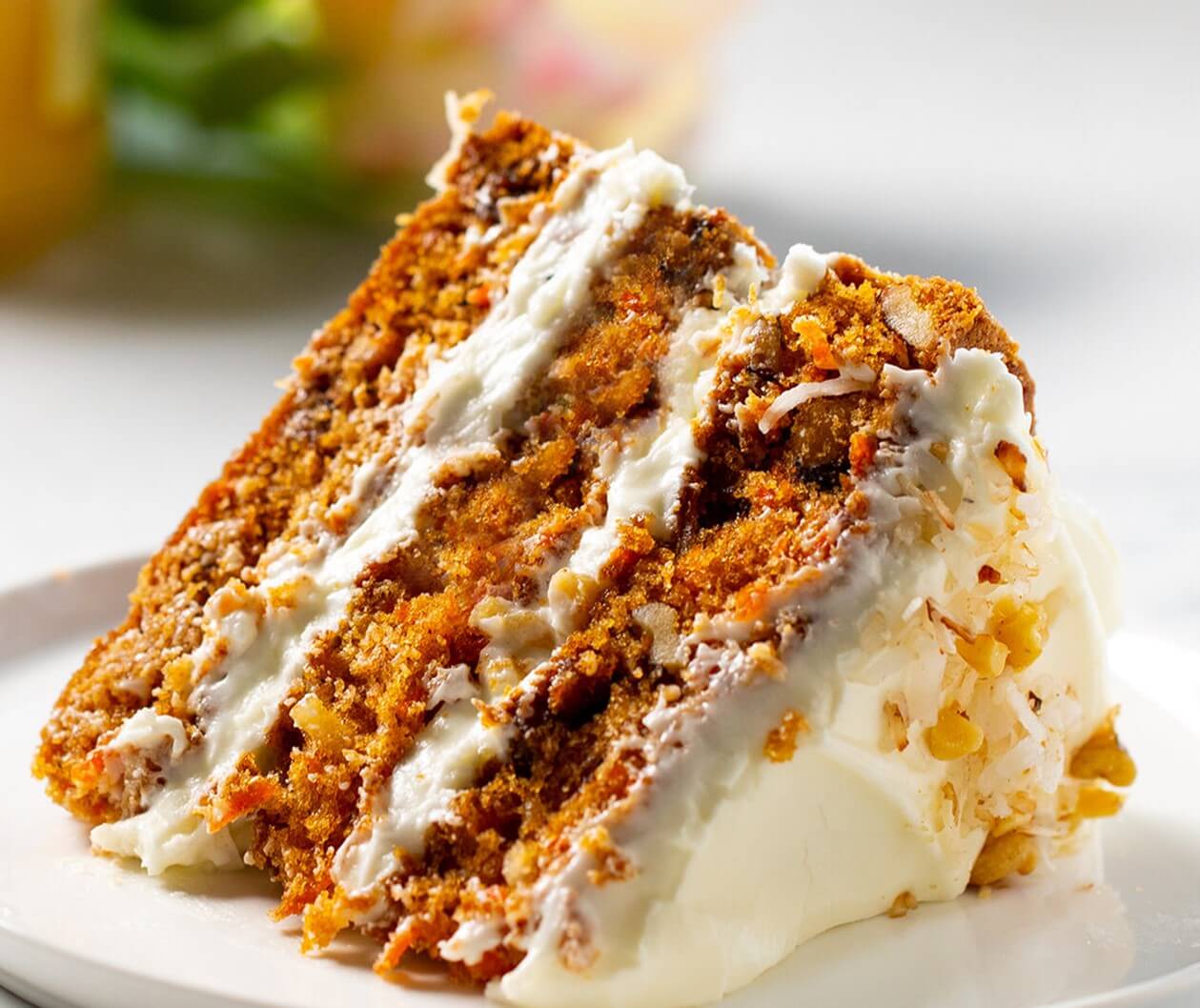 Delicious slice of moist cake made with Premix Carrot Cake Premix - Professional Bakery Quality Mix topped with cream.