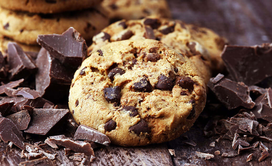 Delicious Cookies Choc Chip Cookies with chunks of chocolate on a rustic wooden background.